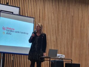 Une intervenante en conférence devant un écran un micro à la main