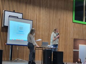 2 intervenantes en conférance devant un écran dont l'une tient un micro