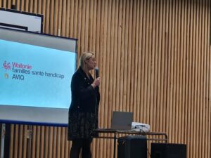 Une intervenante en conférence devant un écran un micro à la main