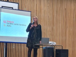 Une intervenante en conférence devant un écran un micro à la main