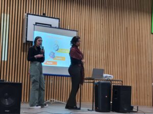 2 intervenantes en conférance devant un écran dont l'une tient un micro